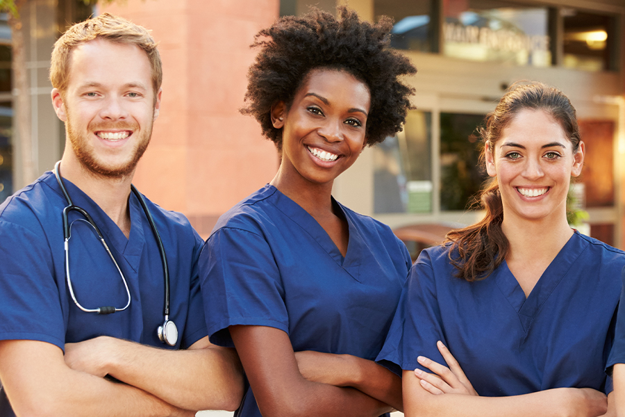 group of 3 smiling students in blue scrubs